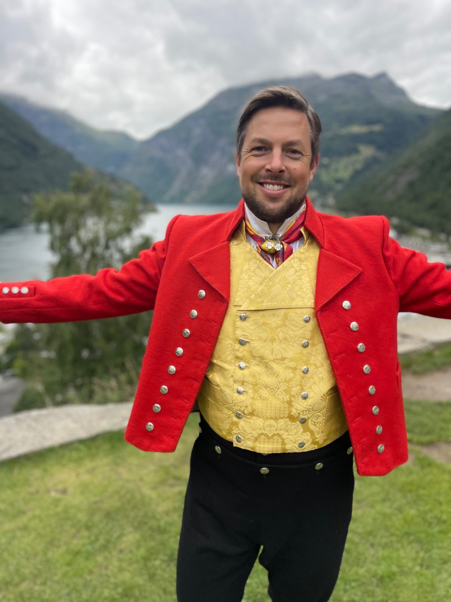 Aleksander, skaper av Norgesliste, i vestfoldbunad foran Geirangerfjorden